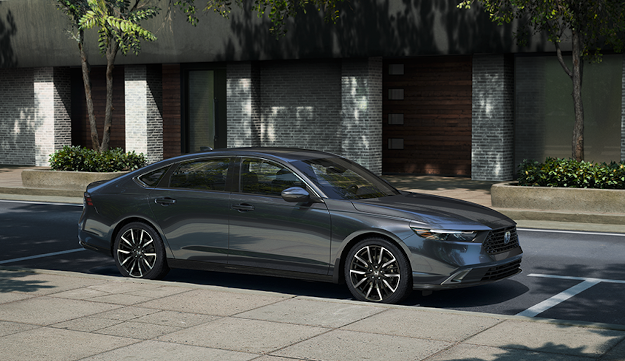 A grey Honda Accord parked beside a sidewalk.