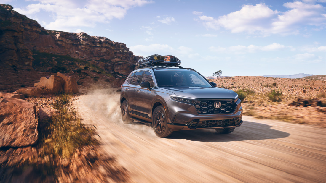A dark grey Hodna CR-V driving down a dirt road.