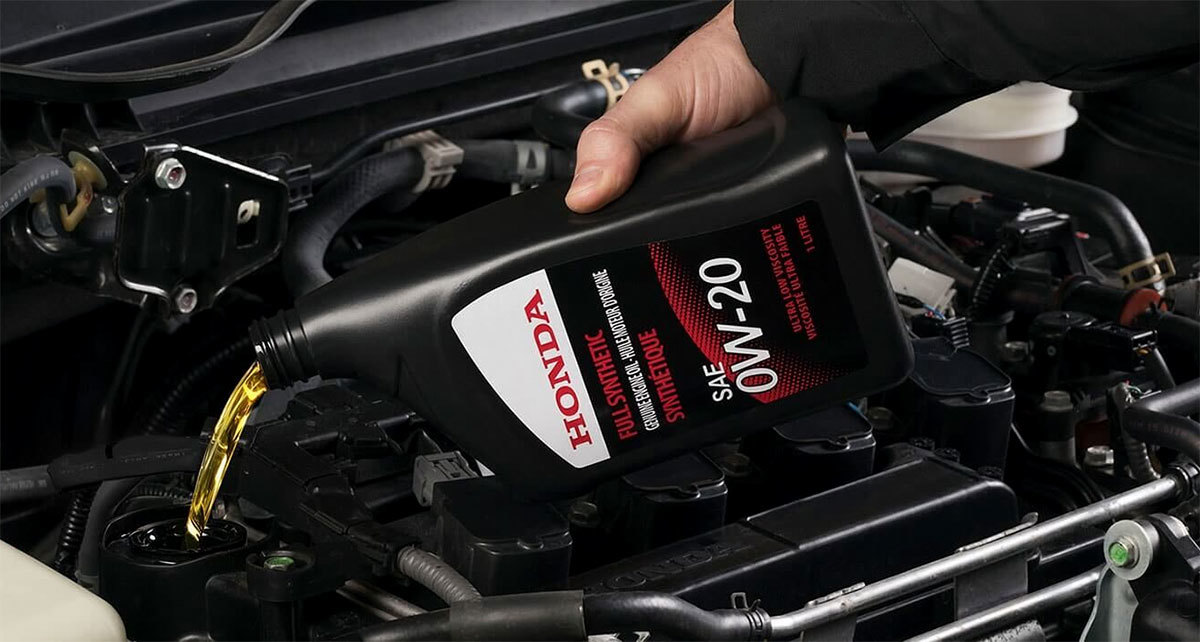 Honda oil change service with a technician working near engine oil